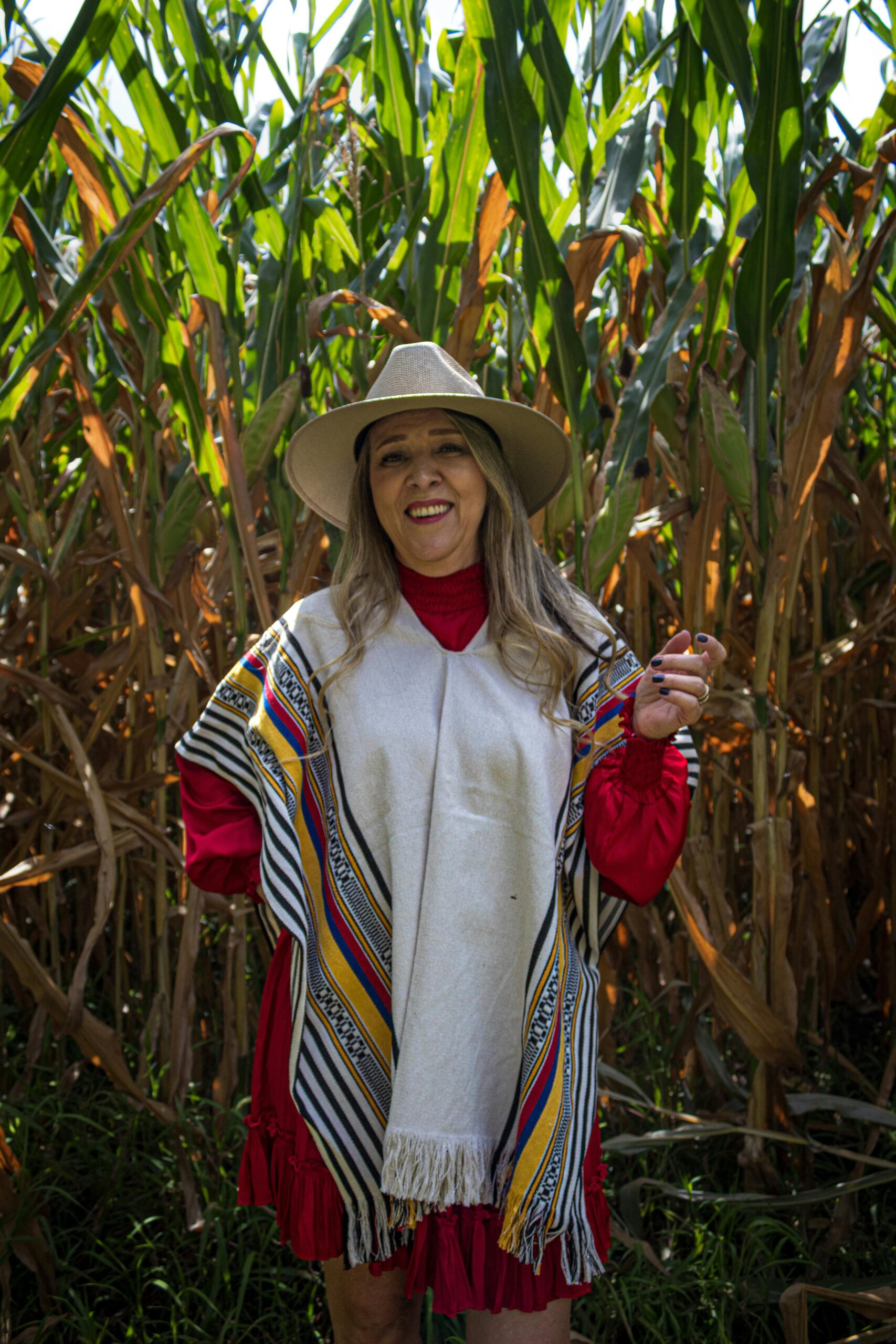 Woman in traditional Mexican attire smiling among cornfields in Santiago de Querétaro.